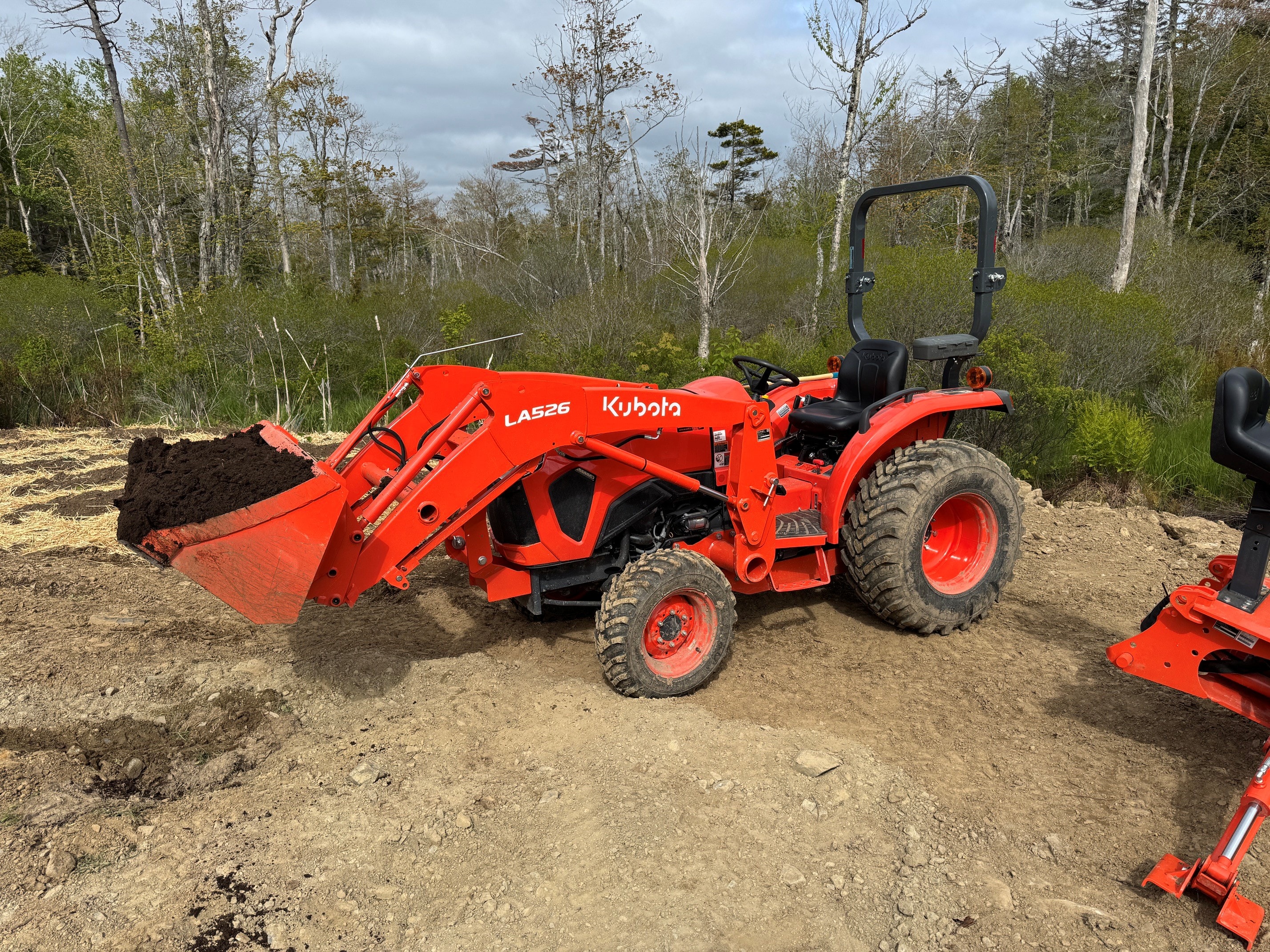Kubota L2502 with LA526 loader moving soil — action shot