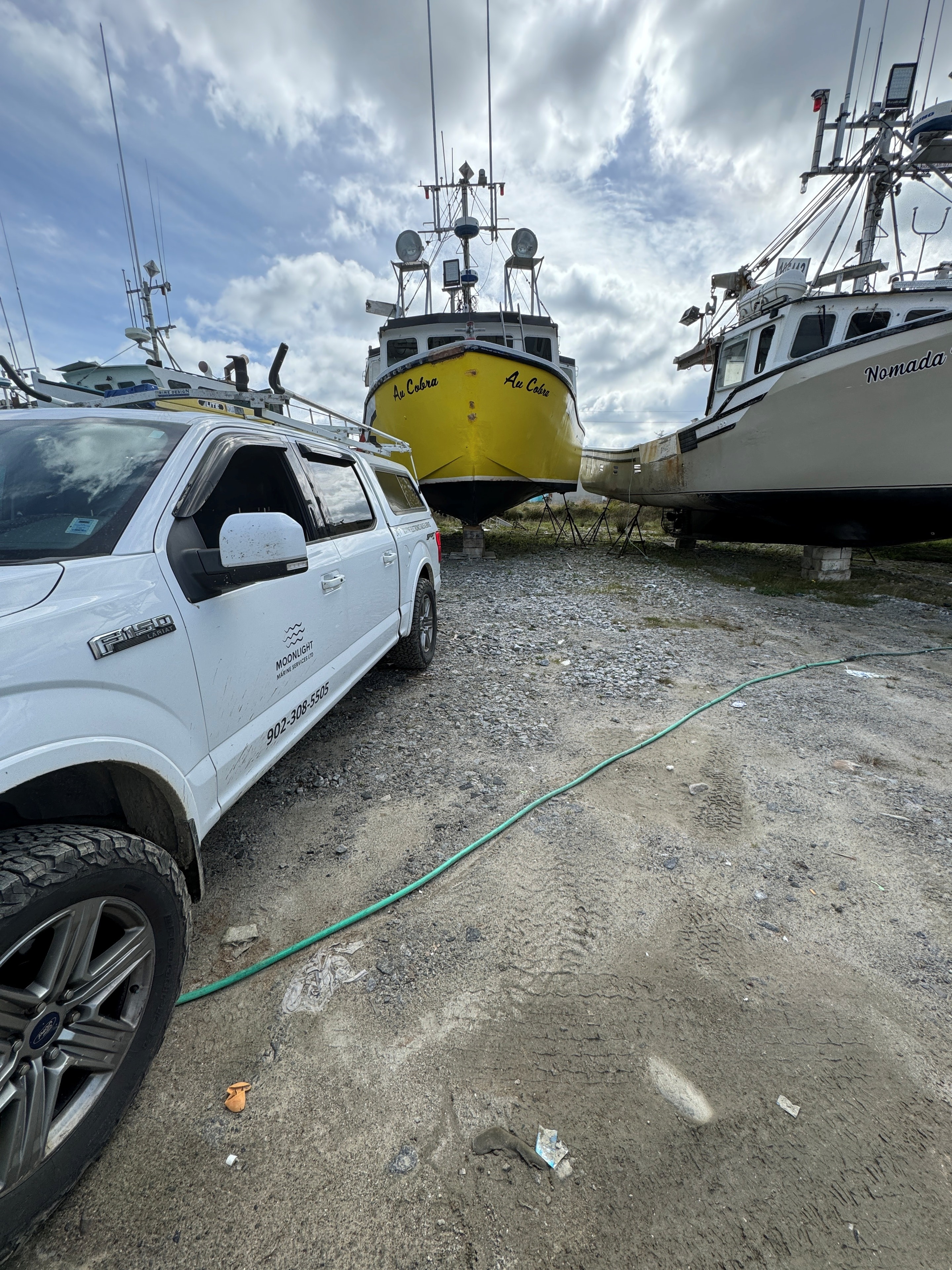 Moonlight Marine Services truck parked beside vessels on the hard